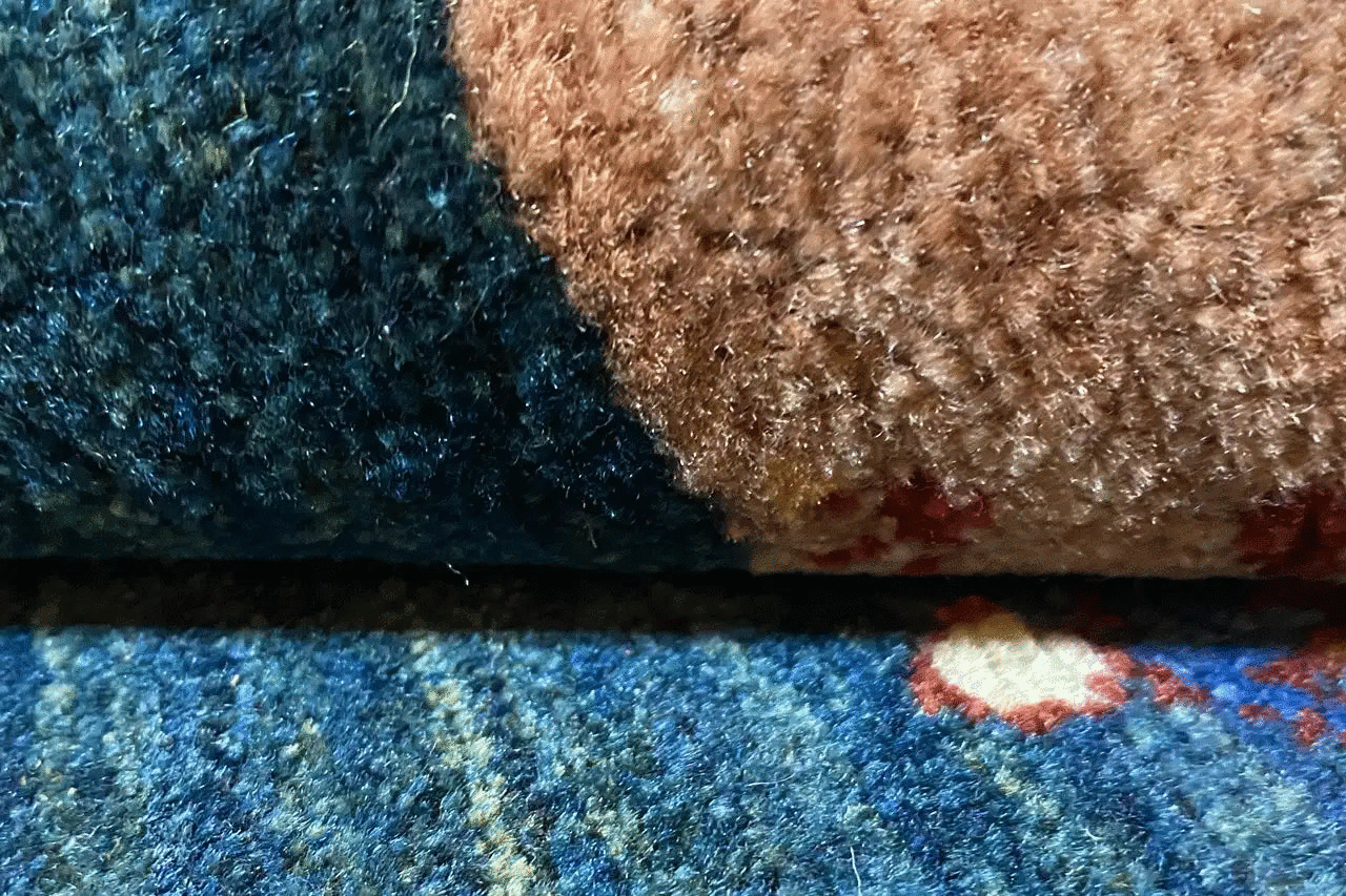 Carpet detail with blue pile, brown and beige stripe, and colorful dots