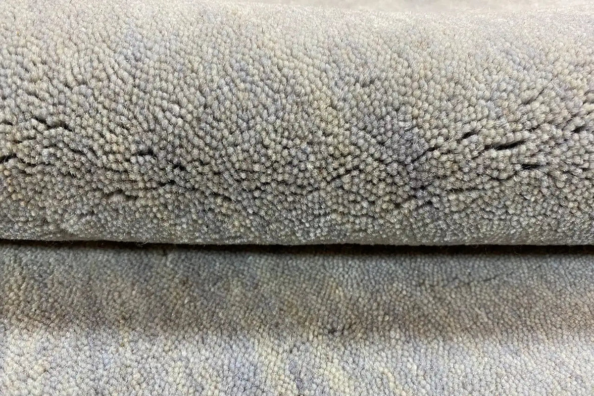 Gabbeh rug, light gray high-pile with visible weave structure, close-up of the edge