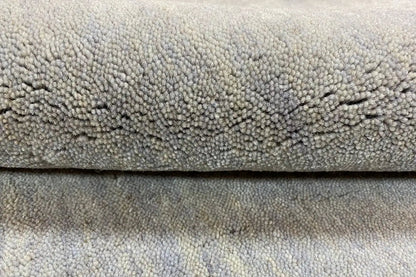 Gabbeh rug, light gray high-pile with visible weave structure, close-up of the edge
