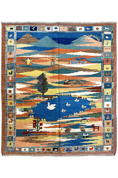 Kilim rug with a landscape motif in blue, beige, and orange, with a fringed border