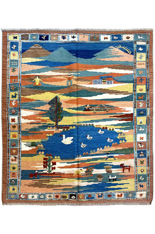 Kilim rug with a landscape motif in blue, beige, and orange, with a fringed border