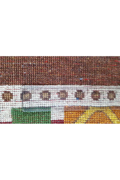 Gabbeh rug “Lori” detail: brown woven base with a white ornamental stripe and green accents