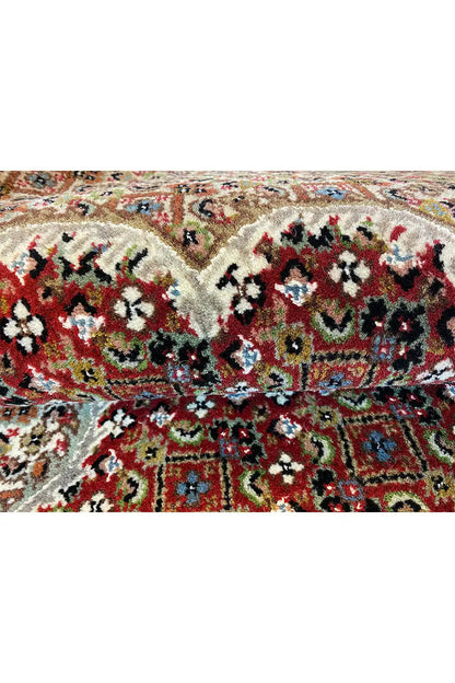 Indo Tabriz rug close-up: dense floral patterns in red, beige, black, and blue