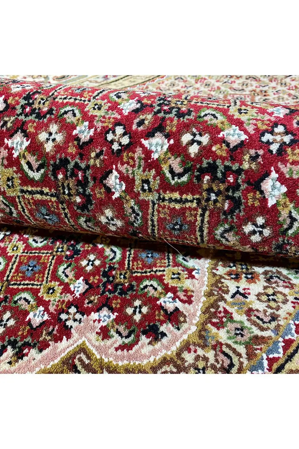 Carpet roll with a dense floral and vine pattern in red, green, and cream