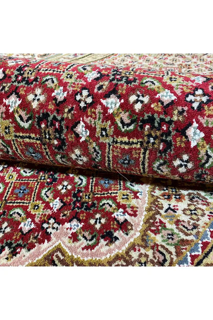 Carpet roll with a dense floral and vine pattern in red, green, and cream