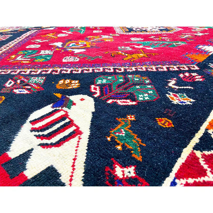 Close-up of a Shiraz rug: red pattern with a white animal, vibrant colors, and borders.