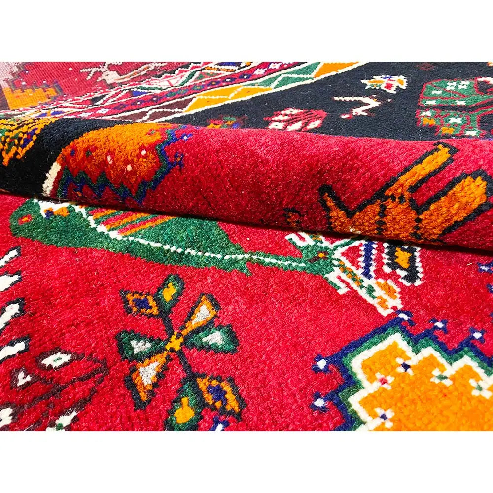 Close-up of the pile of a Shiraz rug: red and dark blue pattern with colorful accents.