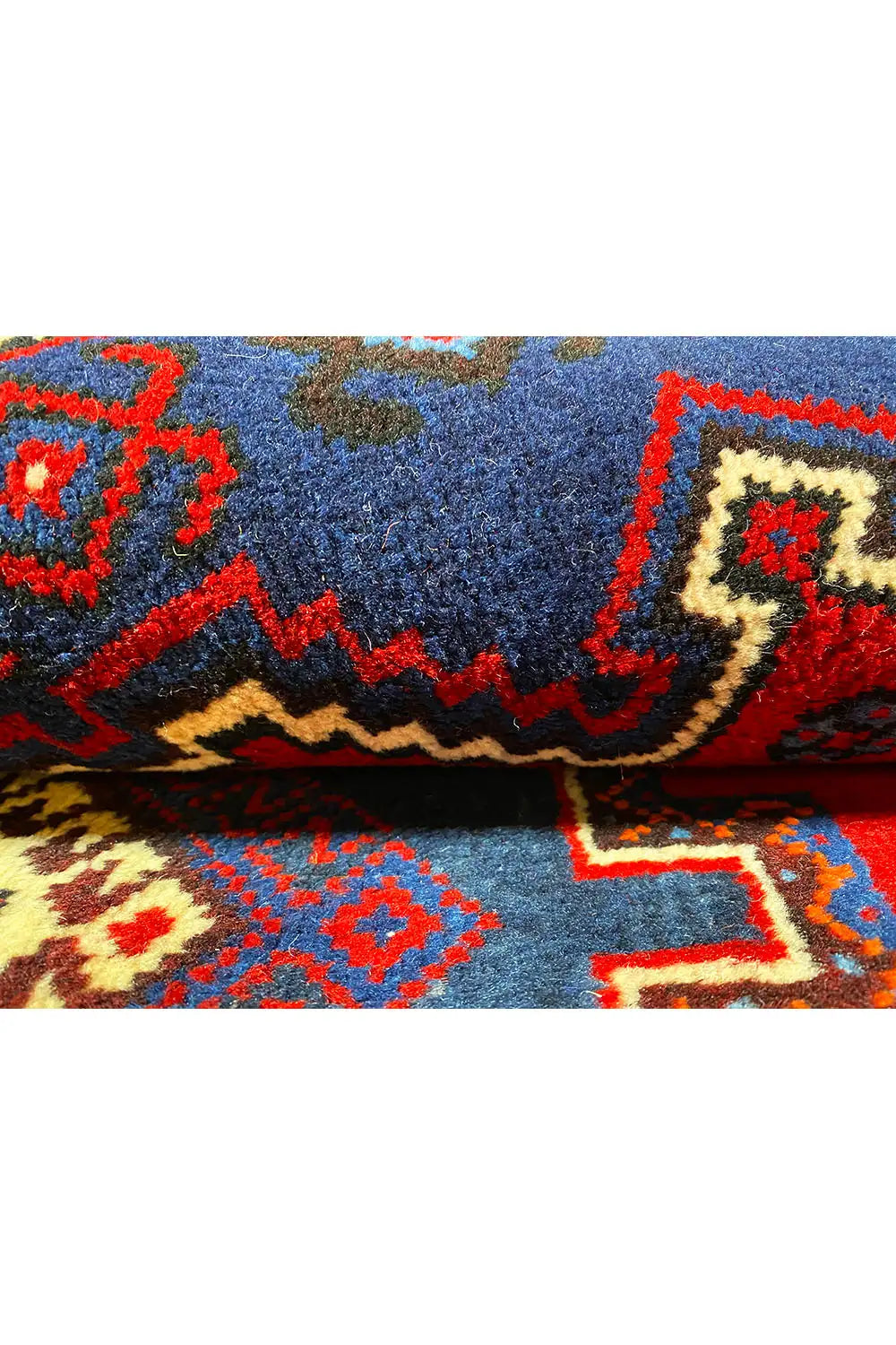 Carpet detail with blue pile and red ornamental borders on a beige background