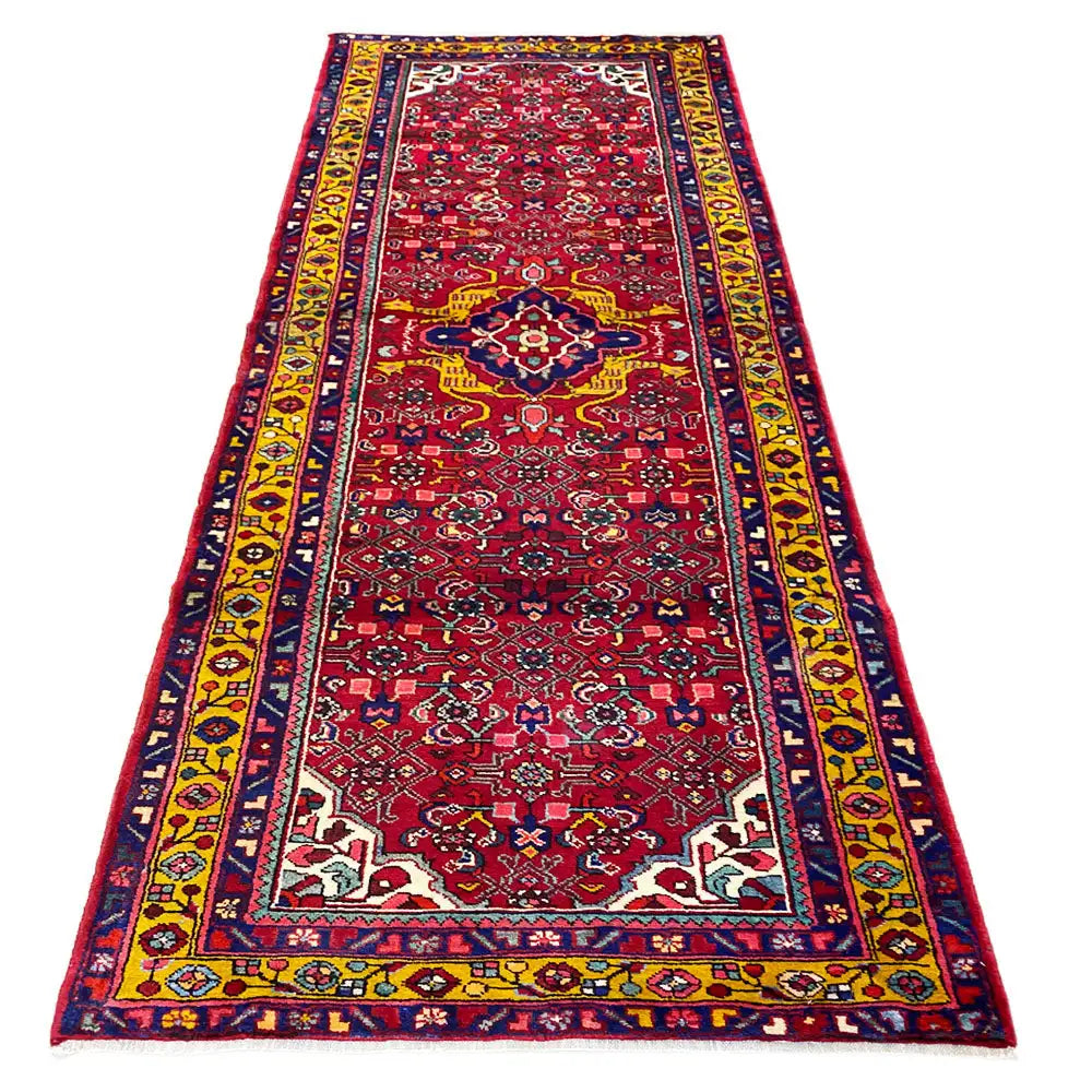 Hamadan runner with a red medallion pattern, border bands in blue, yellow, and white