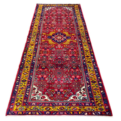 Hamadan runner with a red medallion pattern, border bands in blue, yellow, and white