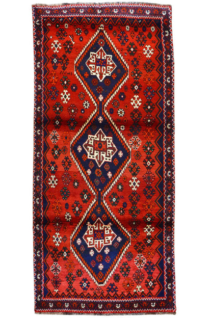 Rectangular red runner with a blue central ornament and zigzag border