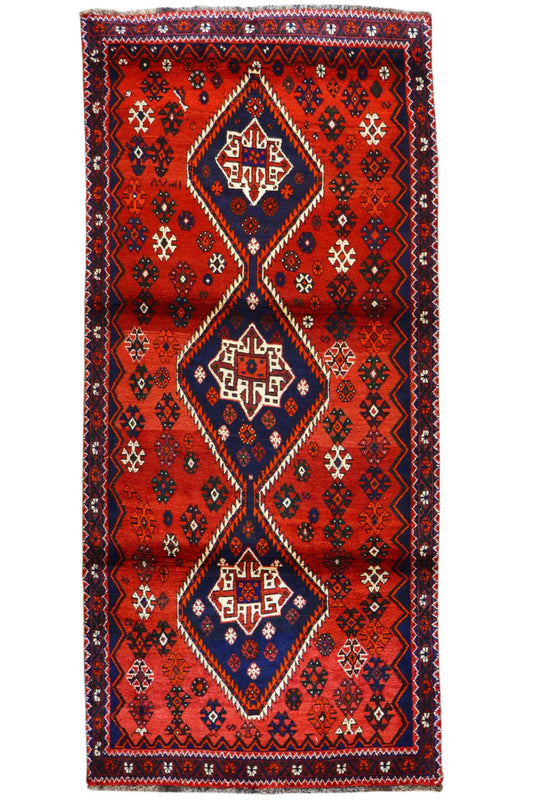 Rectangular red runner with a blue central ornament and zigzag border