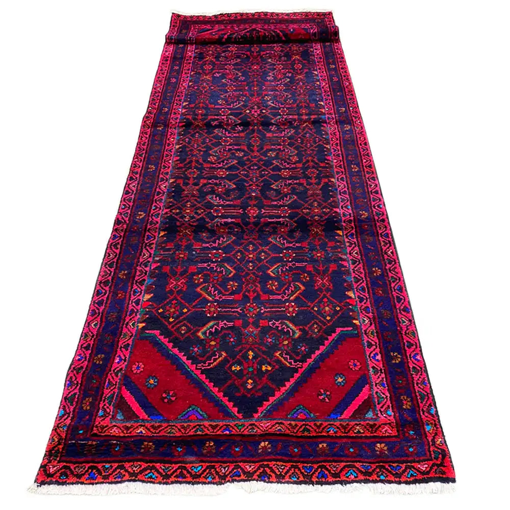Oriental runner rug with soft pile and a large medallion, pink and blue on a dark background