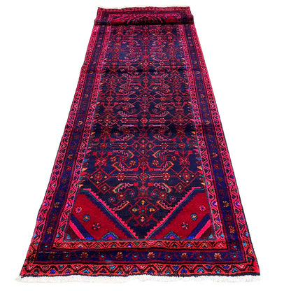 Oriental runner rug with soft pile and a large medallion, pink and blue on a dark background