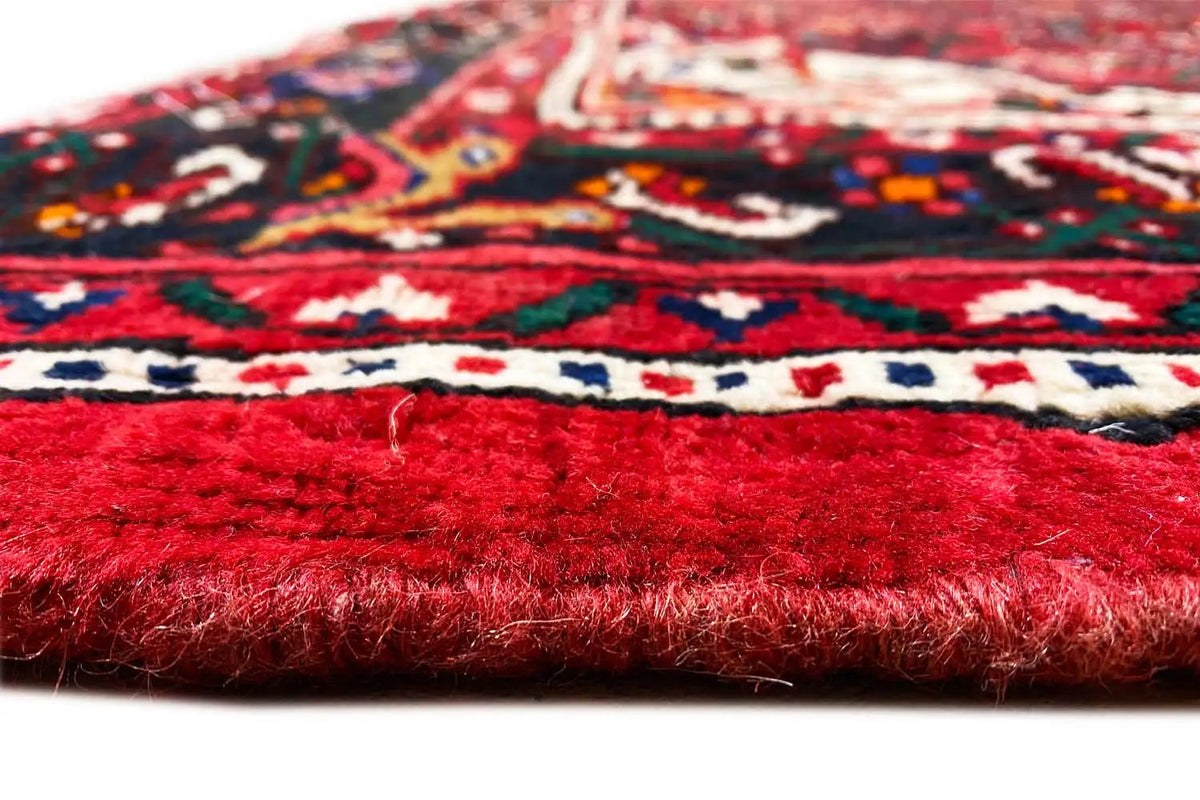 Carpet edge in close-up: red pile with a clear seam and multicolored patterns