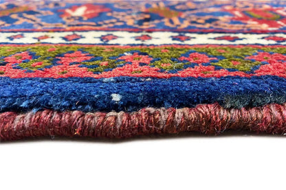View of the carpet edge: blue pile with a red accent and a fringed side border