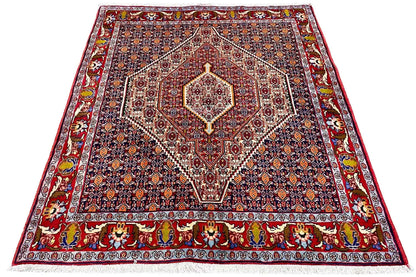 Rectangular Oriental rug with a dark blue patterned field and red border ornamentation