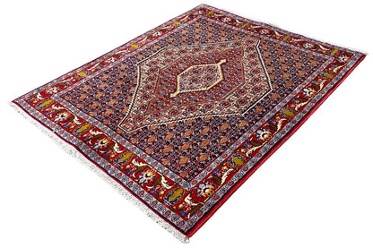 Oriental rug with a red inner border and multicolored medallion, shown diagonally