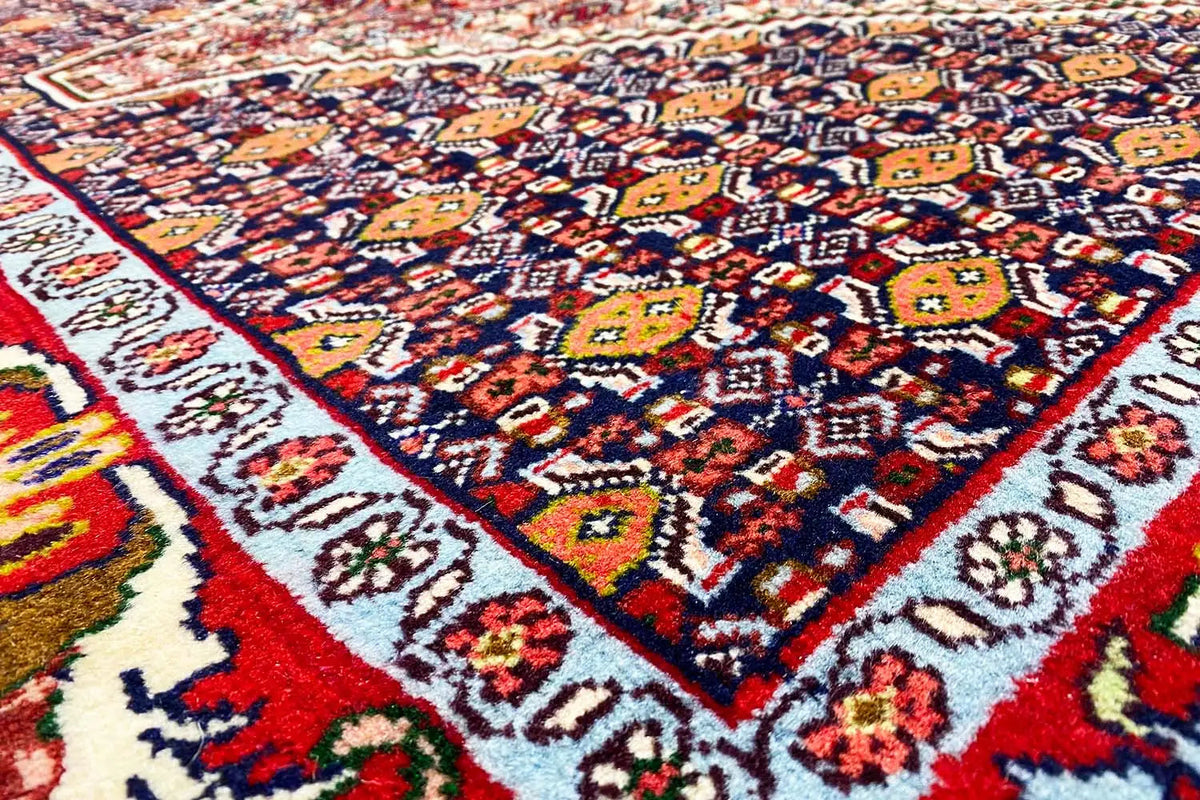 Close-up of an oriental rug: colorful decorative motifs, red border and blue field
