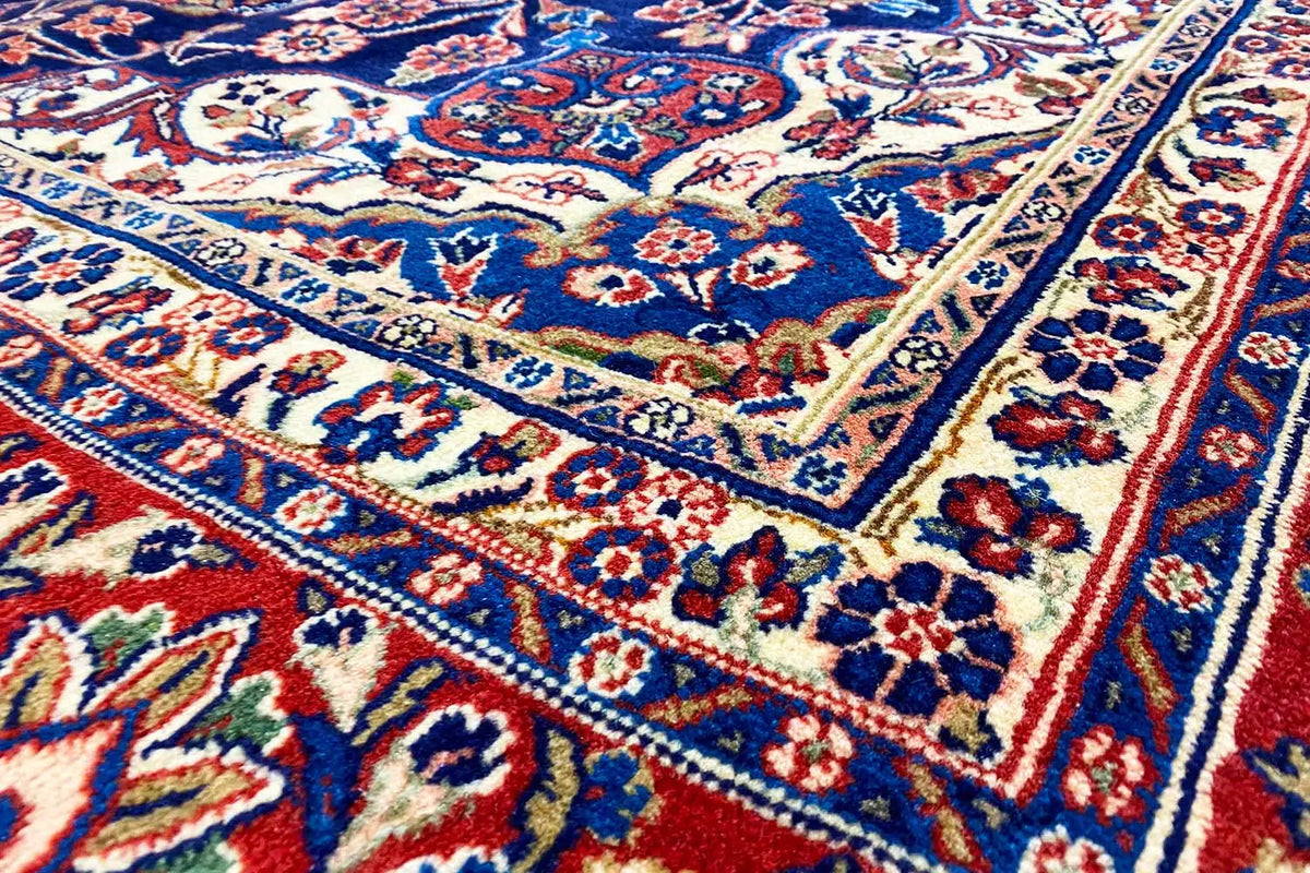 Carpet detail view: blue-red floral motifs, a jagged border line, and fine ornamental stripes