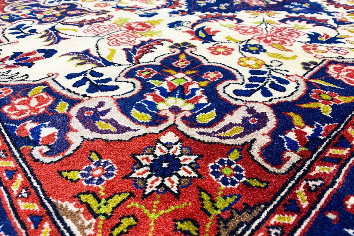 Close-up: carpet pattern with colorful floral motifs in blue, red, yellow, and green on cream
