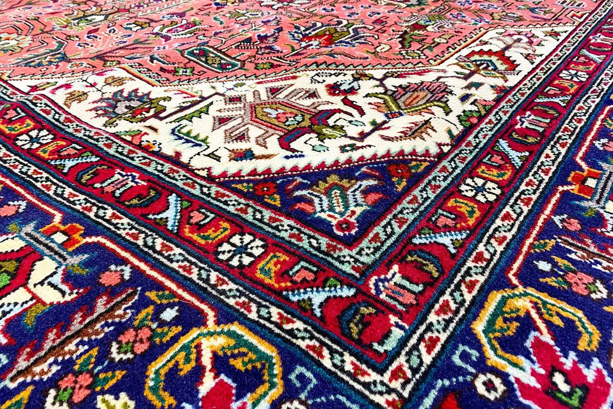 Detail view of a Tabriz rug: colorful floral and geometric patterns in red, blue, and yellow