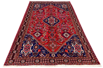 Rectangular rug with a red field, blue-and-white border, and ornaments