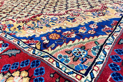 Hamadan rug detail, colorful floral and star pattern on a beige background with blue/red