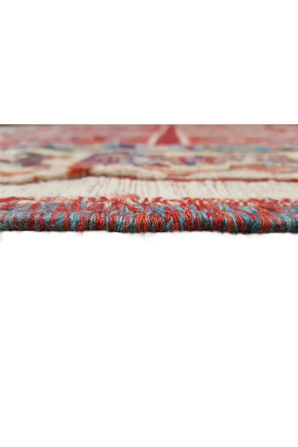 Carpet detail: red woven edge with multicolored border and fringe, side view.