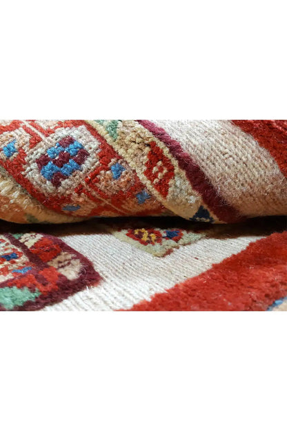 Oriental rug detail: multicolored patterns on a red background with visible weave texture