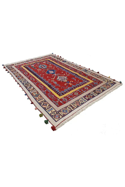 Oriental rug with a red patterned field, blue-red border design, and fringes at the corners