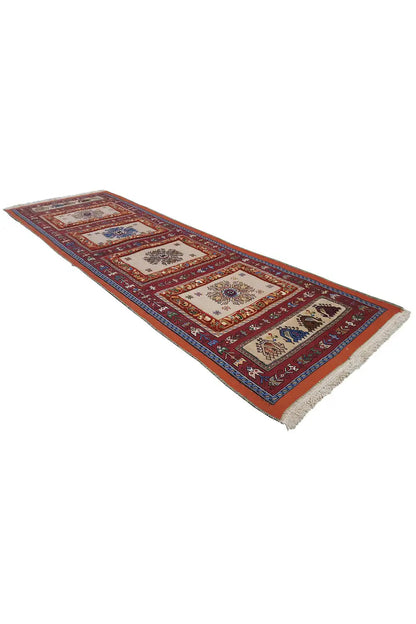Runner rug with a block medallion design, dark red and blue, with fringed edges.