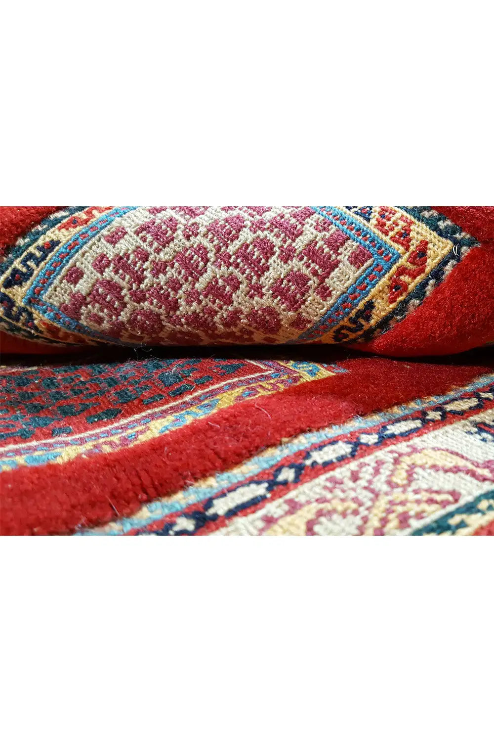 Soumak rug: close-up with a red background, blue accents, a cream-colored pattern, and pile.