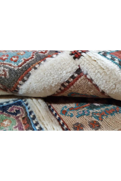 Carpet detail: dense pile section and knotted transition, beige with blue-red accents