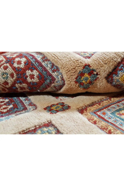 Carpet detail with a cream-colored background, blue-red patterns, and knotted pile tufts