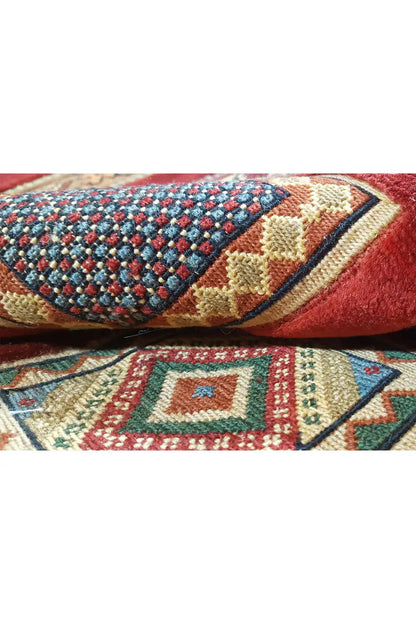 Folded carpet view with a blue and red diamond pattern, beige accents, and fringes