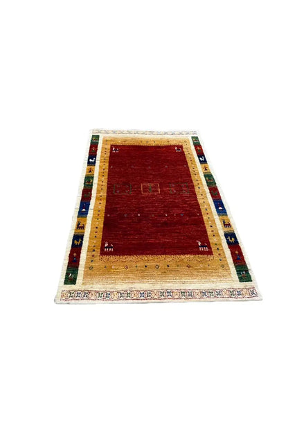 Gabbeh rug (123x80 cm) in angled view: red field, beige border, blue/green accents