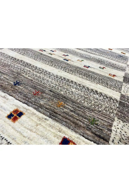 Gabbeh rug detail: gray texture, light stripes, and small colorful ornaments