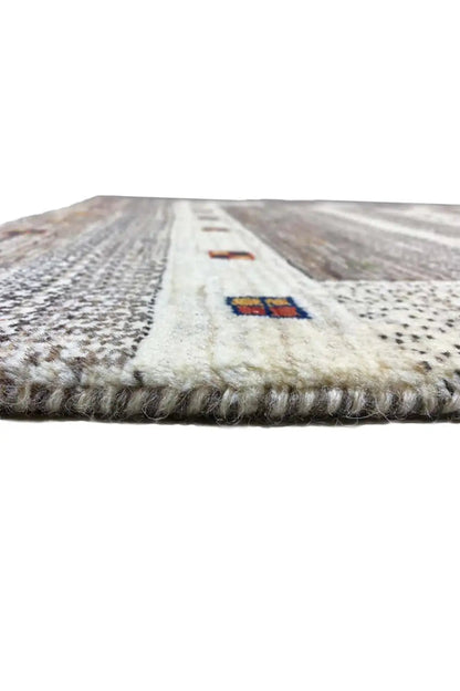 Gabbeh rug edge view: light surface, colorful cartridges, short fringes