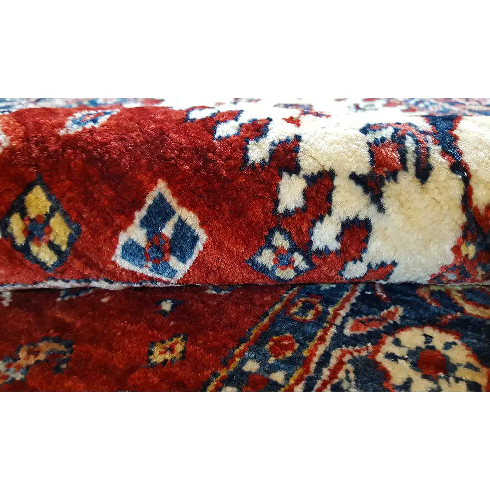 Close-up of the carpet: red pile with a blue ornamental border and a cream-colored edge