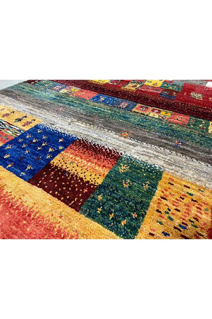 Gabbeh rug: richly detailed pile with patterned color blocks in blue, green, and orange.