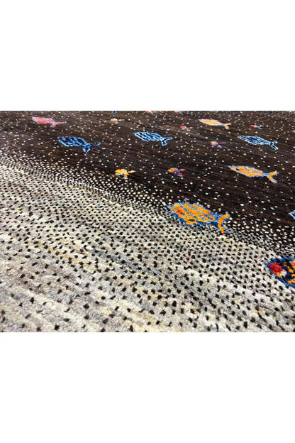 Close-up of a Gabbeh rug: black-and-gray woven texture with colorful fish motifs