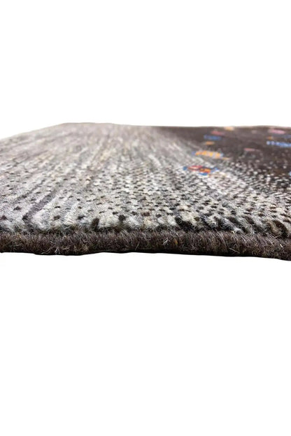 Gabbeh rug edge view: gray area, black patterned section, visible selvedge