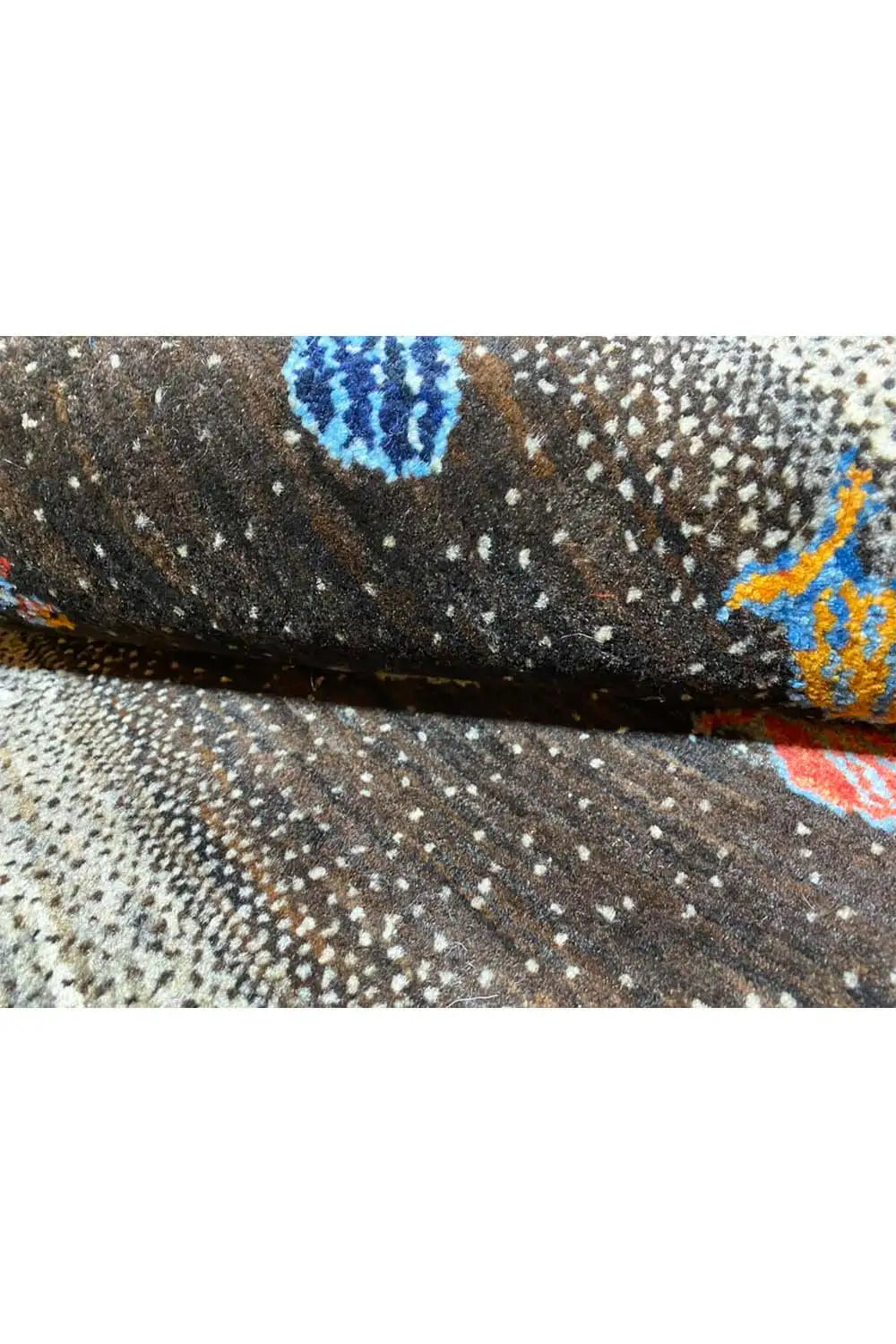 Gabbeh rug detail: black background with colorful fish motifs on gray pile