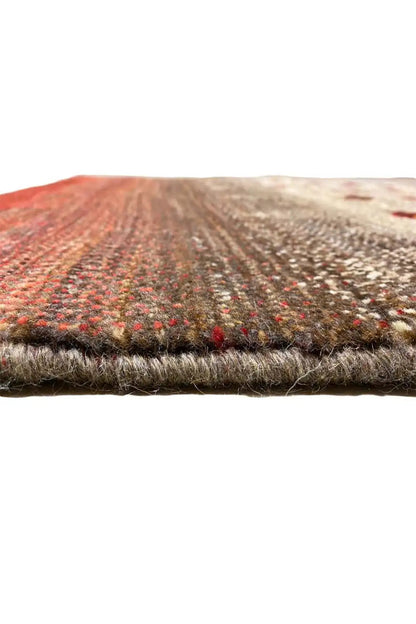 Gabbeh rug detail edge, red-beige textured surface with colored dots along the edge