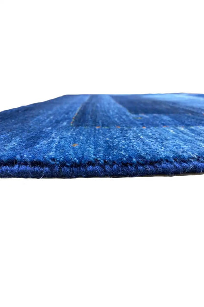Blue Gabbeh rug with visible pile height and folded edge