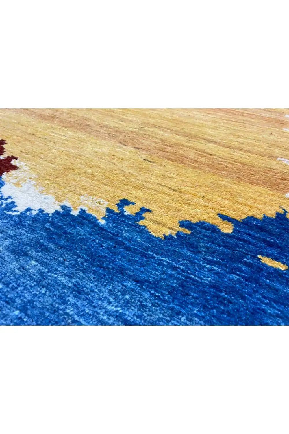 Close-up of a Gabbeh rug: blue area with a yellow-brown patterned section