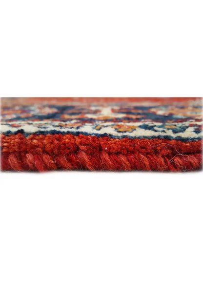 Carpet edge in detail: dense red pile with a multicolored pattern along the edge