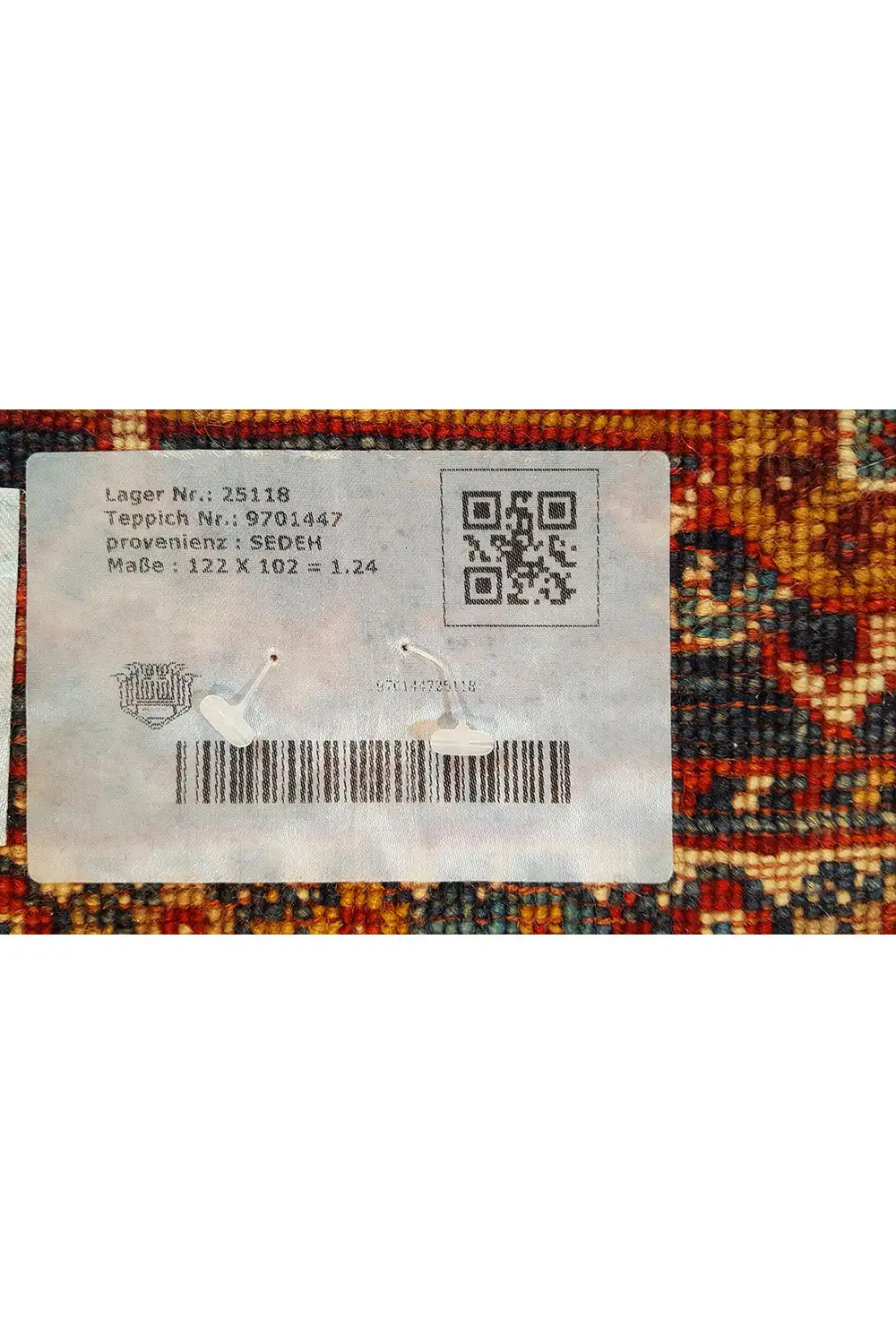 Label on the back of a rug with a QR code, surrounded by a colorful rug pattern