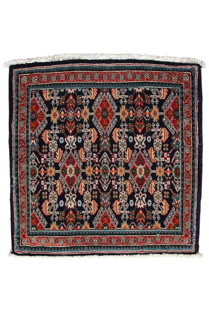 Square oriental rug, dark blue background with a red border and white fringes